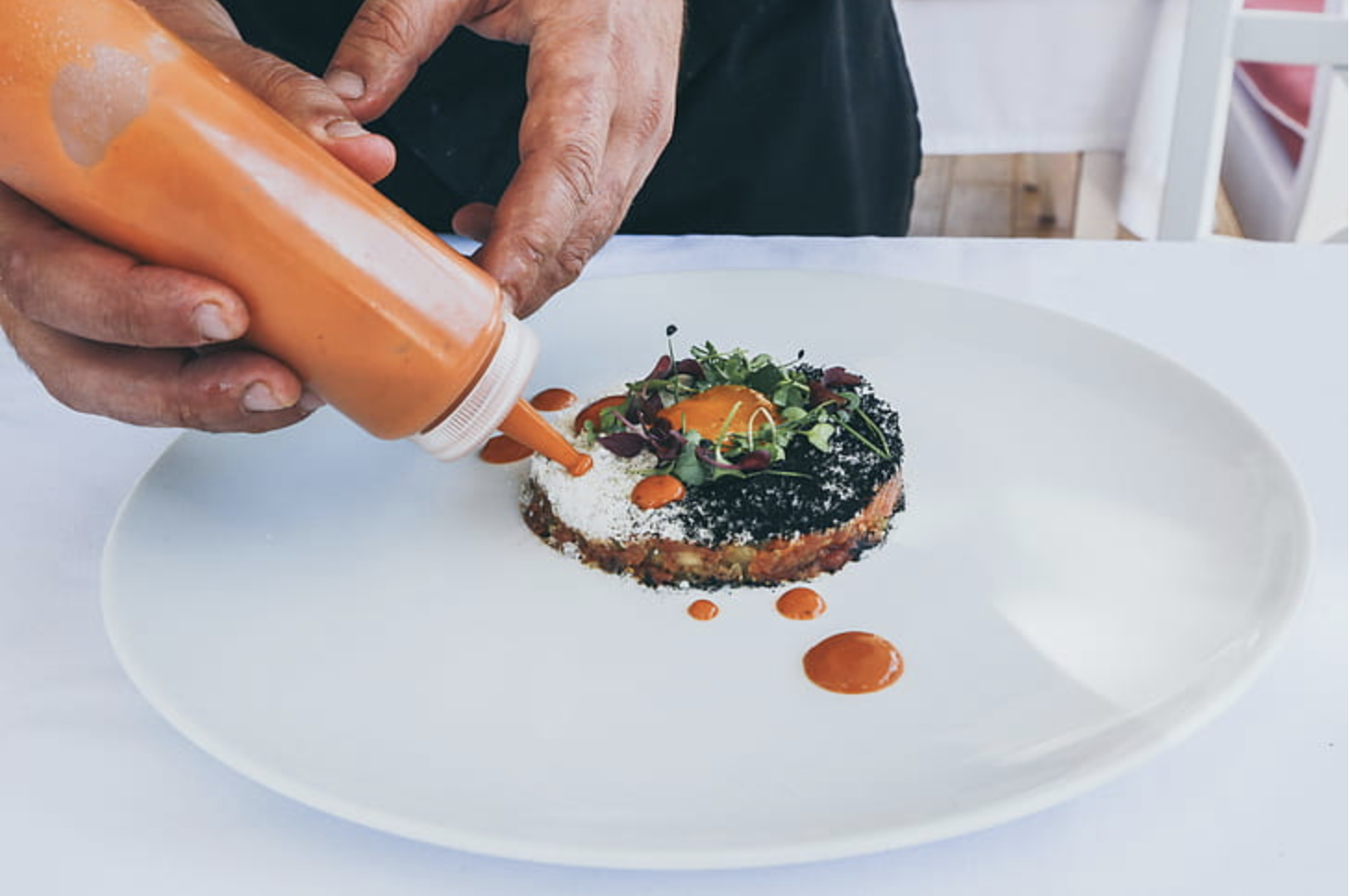 Adding dots of sauce to a plate of food.